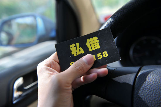 一張寫(xiě)著“私借”和“無(wú)抵押”貸款的卡片被插放到汽車(chē)的門(mén)縫里。卡片上留有聯(lián)系電話，以及“上門(mén)服務(wù)，立即出款”等字樣 圖／CFP